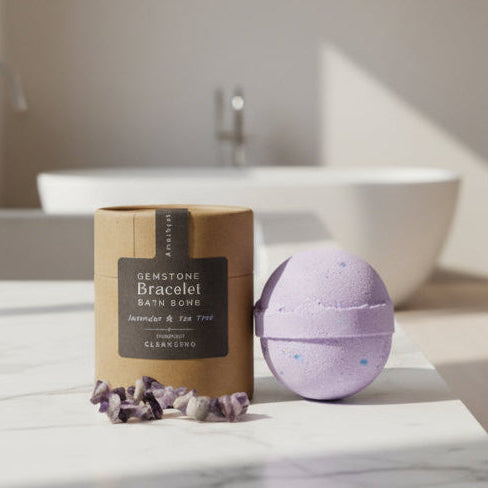 Purple bath bomb with amethyst stones and packaging on a white background
